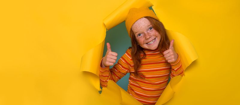 Portrait,Of,Cute,Little,Freckled,Redhead,Child,Breaking,Through,Yellow